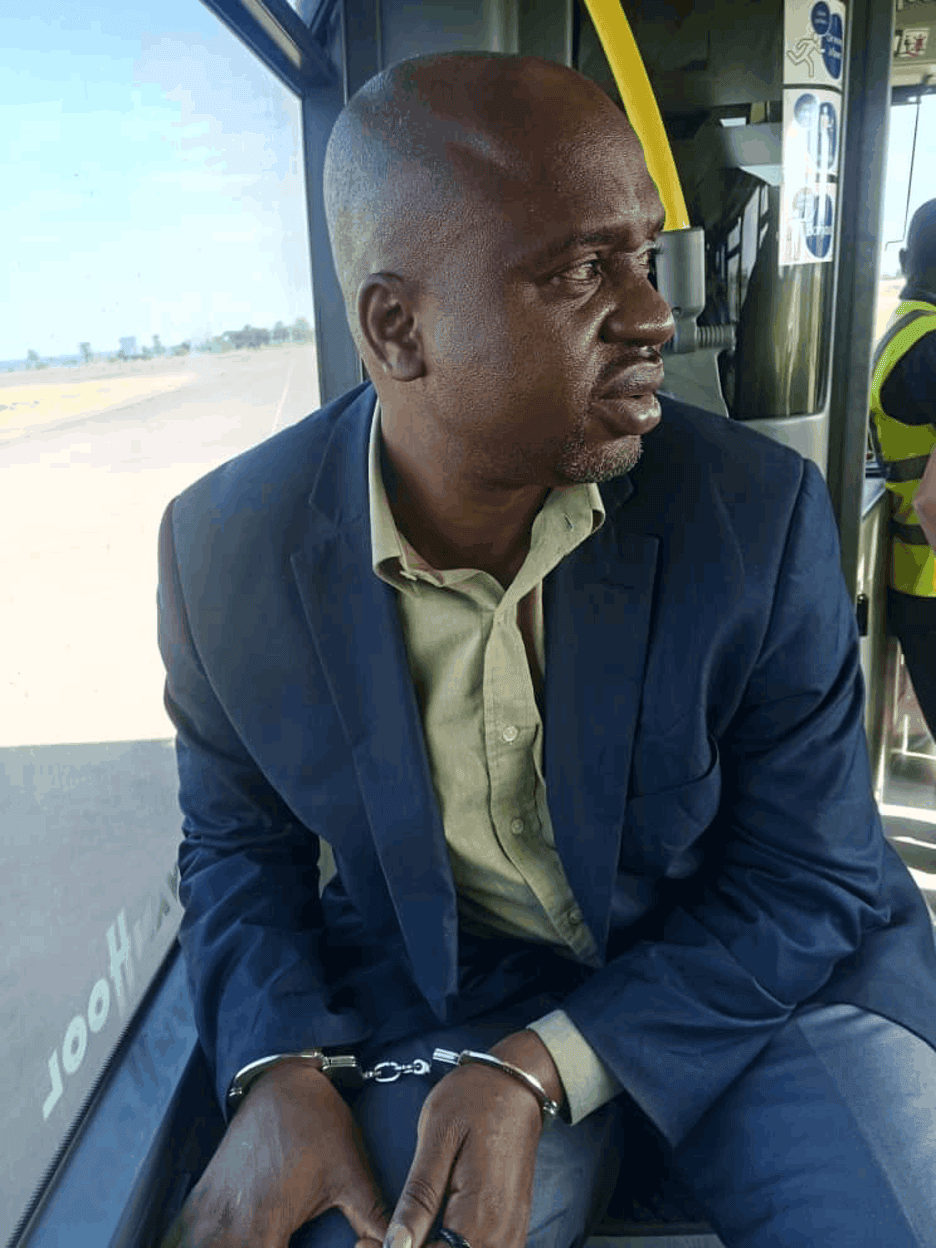 A man on a bus wearing handcuffs.